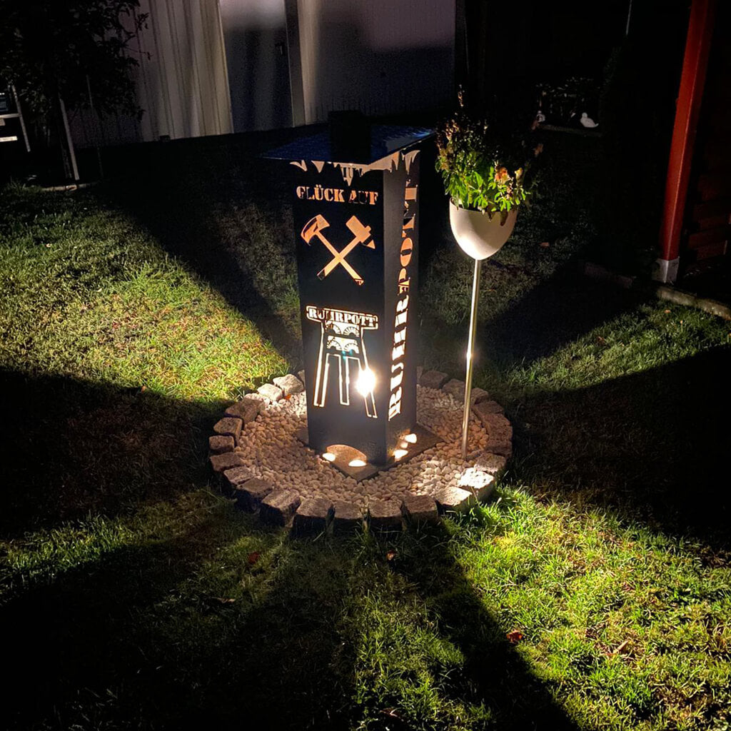Ruhrpott Feuertonne Feuersäule in Schwarz im Garten beleuchtet